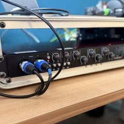 Audio equipment sits in a rack with cables plugged into it.
