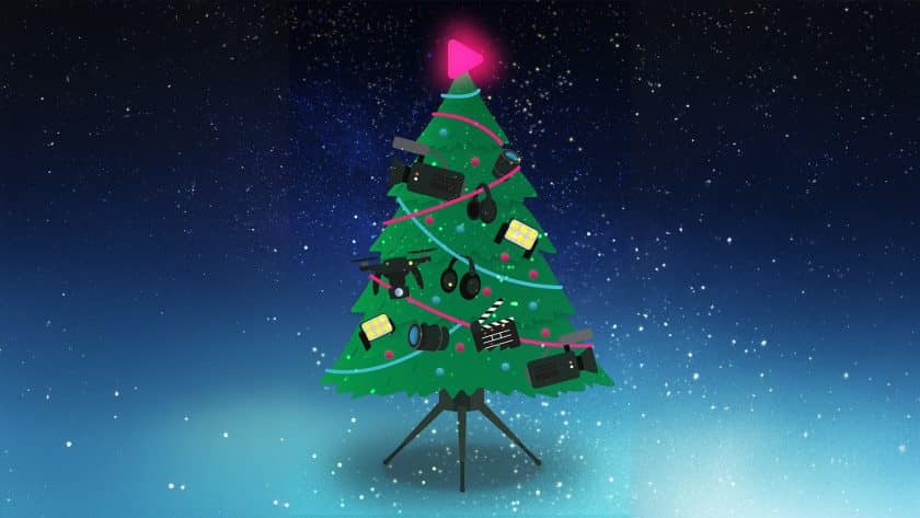 Illustration of a Christmas tree decorated with various film and video production equipment like cameras, lights, lenses, headphones, a drone, and a clapperboard, topped with a pink play button (the Southpoint Films logo) against a starry night sky.