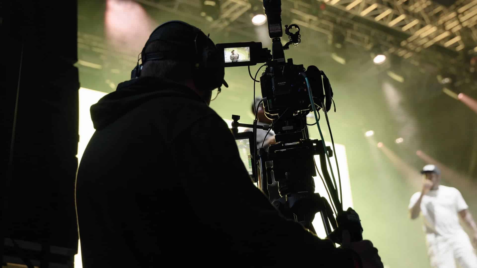 A vibrant music festival scene showcasing lights and equipment for filming.
